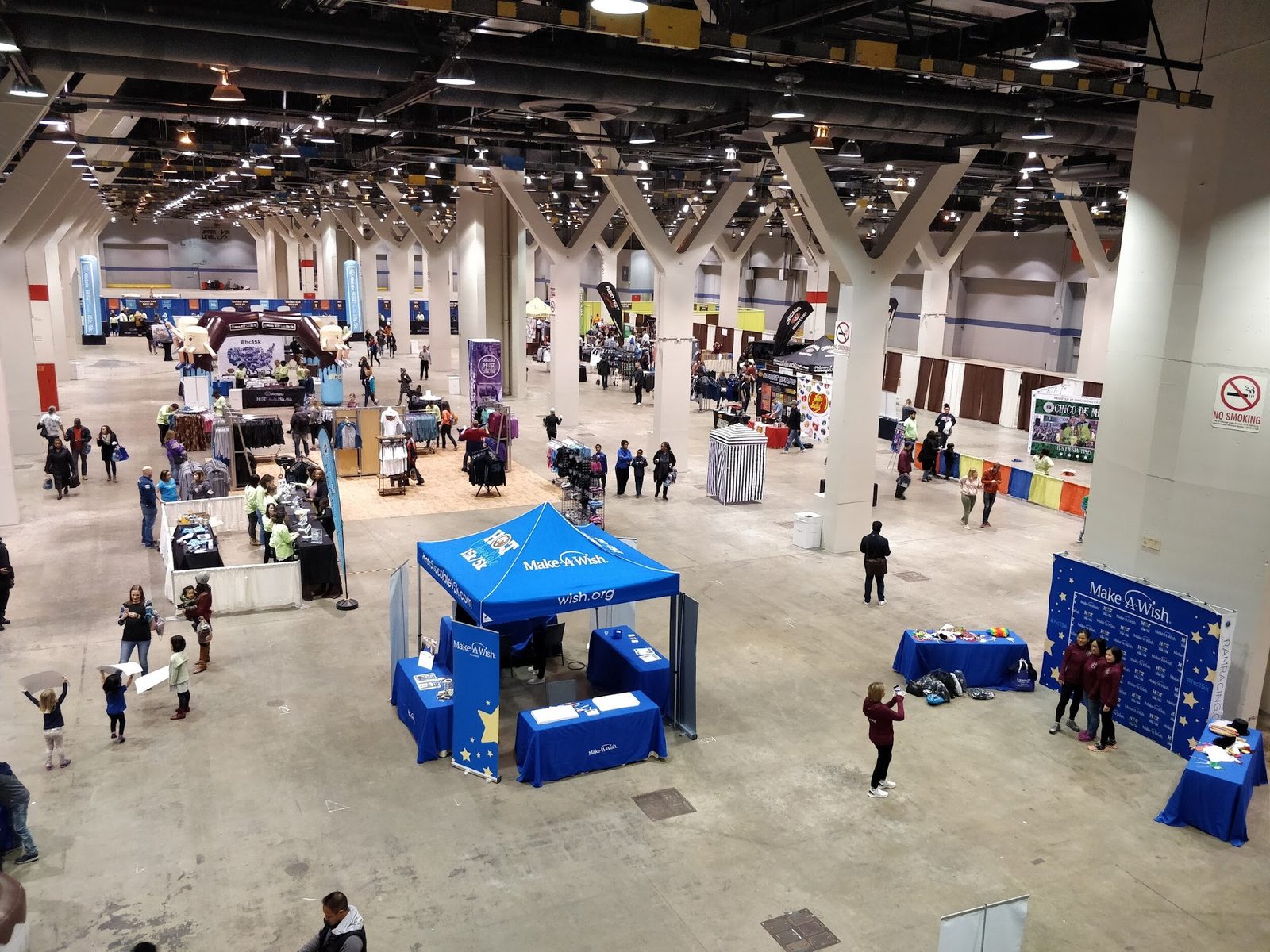 Wide view of a race expo hall at packet pickup, with booths and runners across the floor.